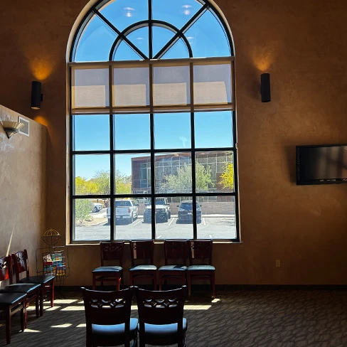Waiting room with tall arched window and chairs at dental office